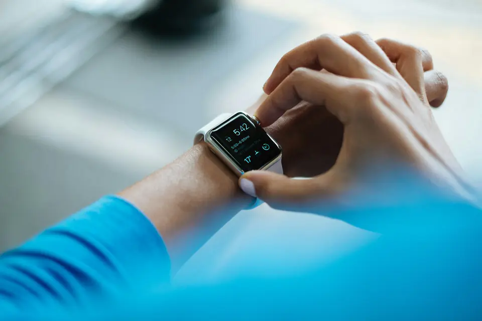 Hands adjusting a smartwatch on a wrist during a run.