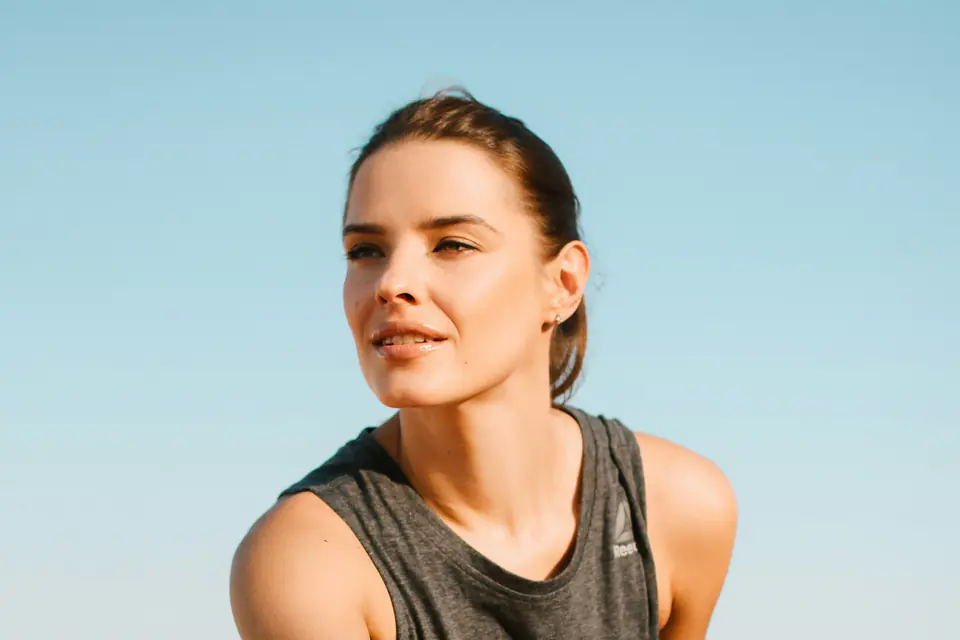 A runner in a grey tank top resting at the side of a run.